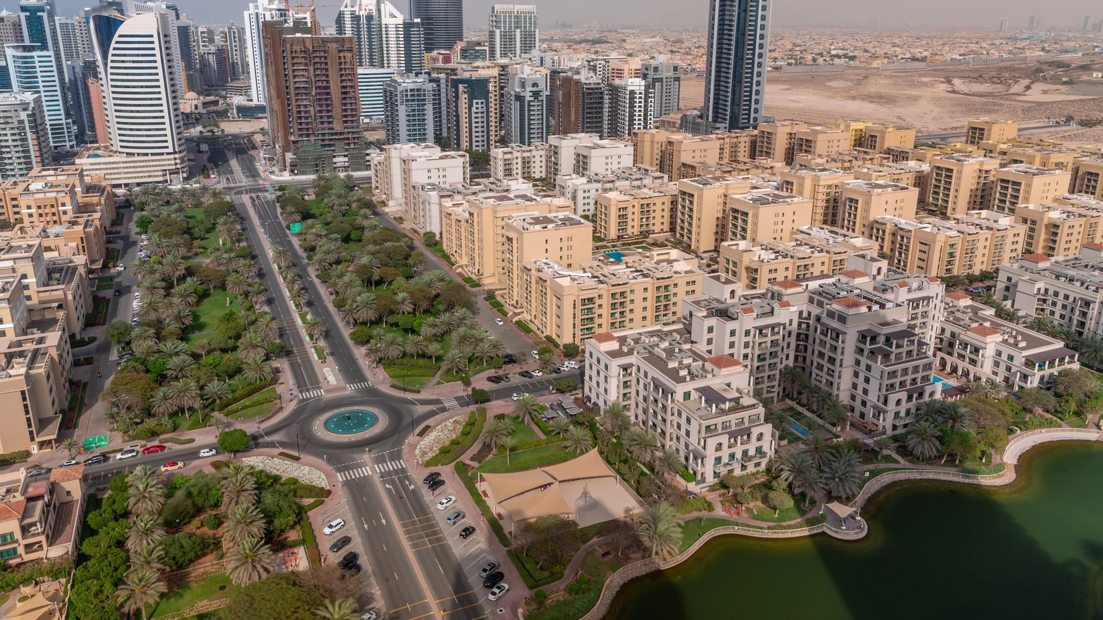Elevated view of residential buildings, palm-lined roads and a landscaped lake