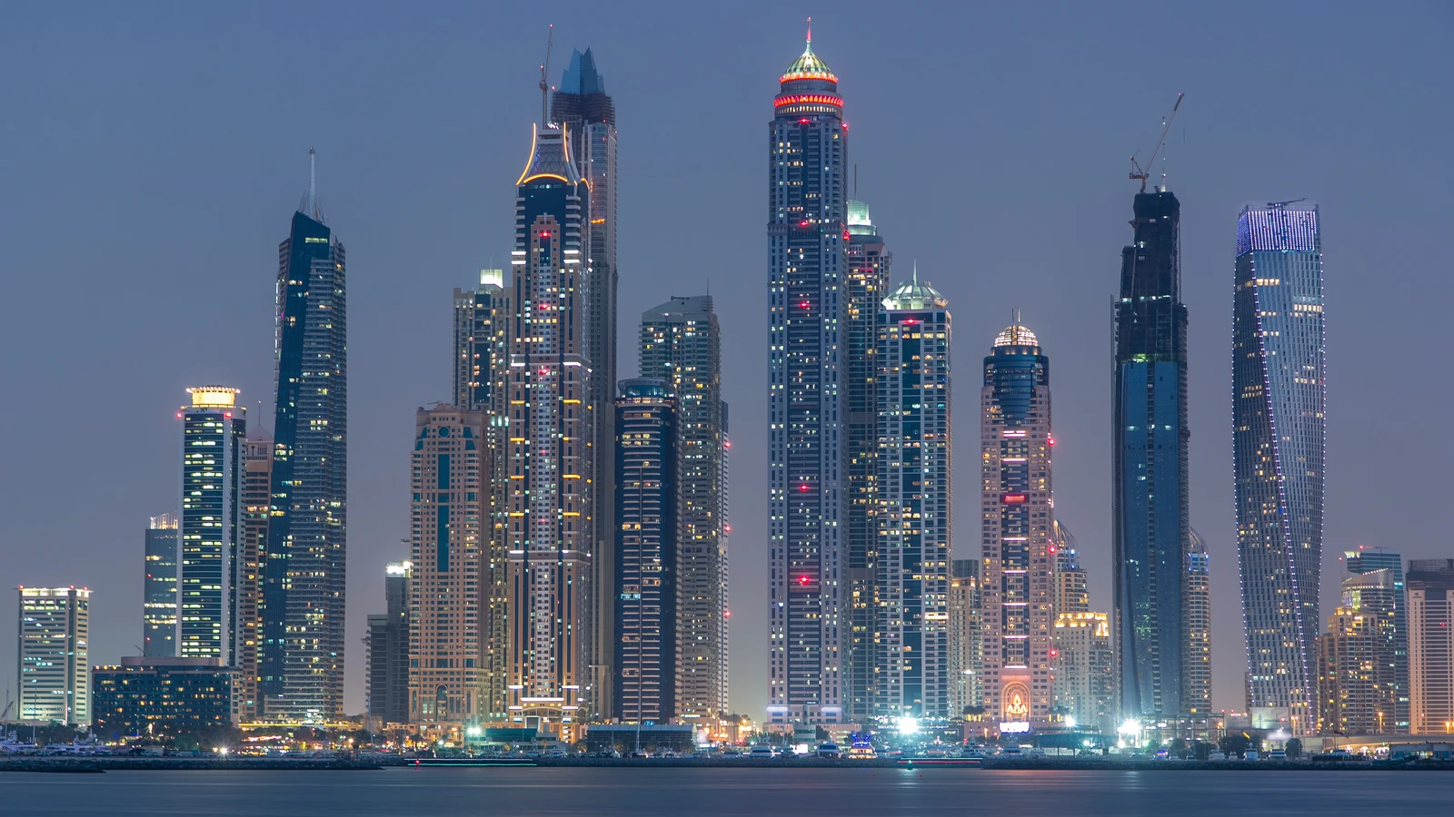 Illuminated Dubai Marina skyscrapers along the waterfront at dusk